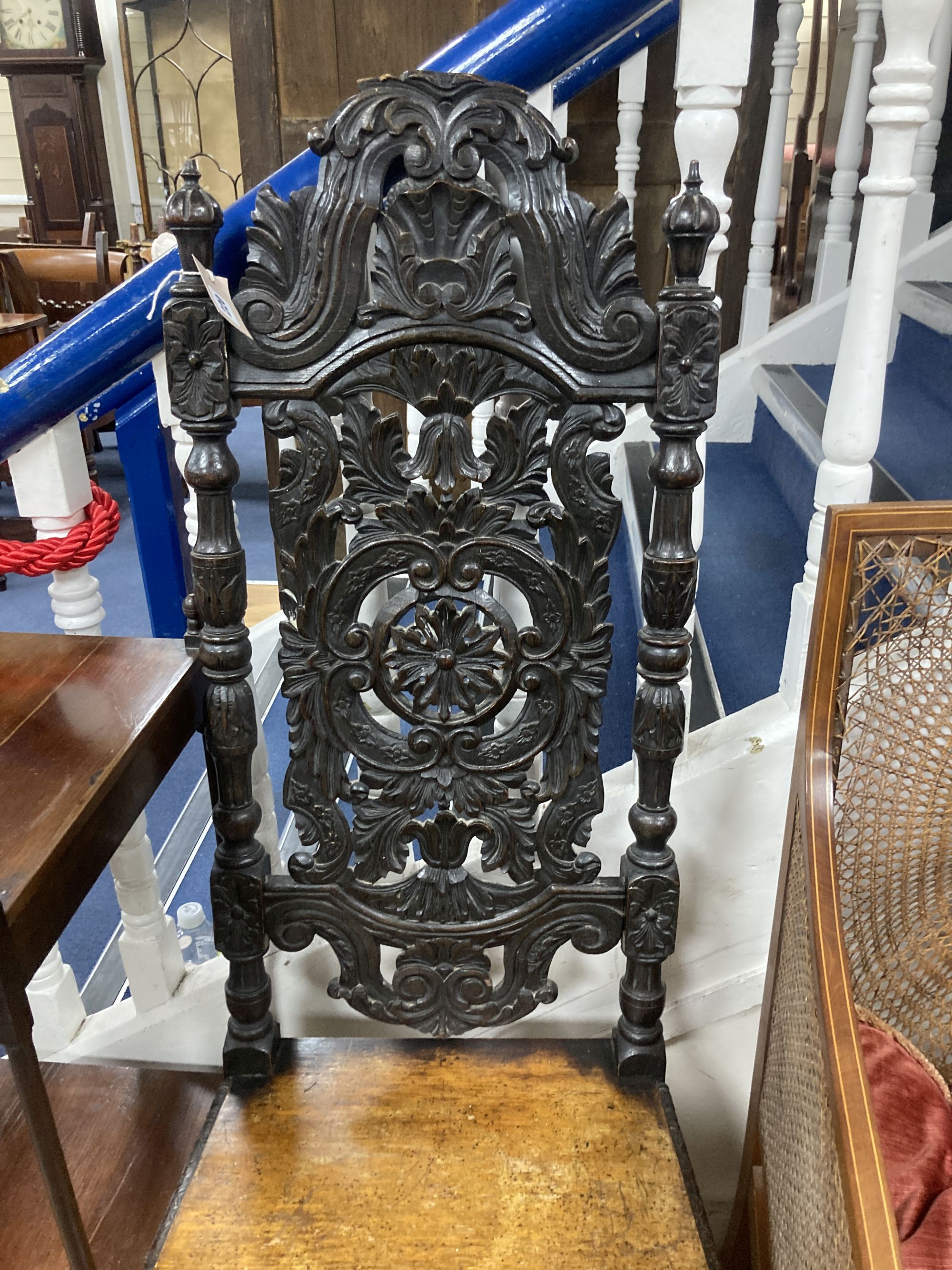 A Flemish carved oak dining chair and an Edwardian bergere chair